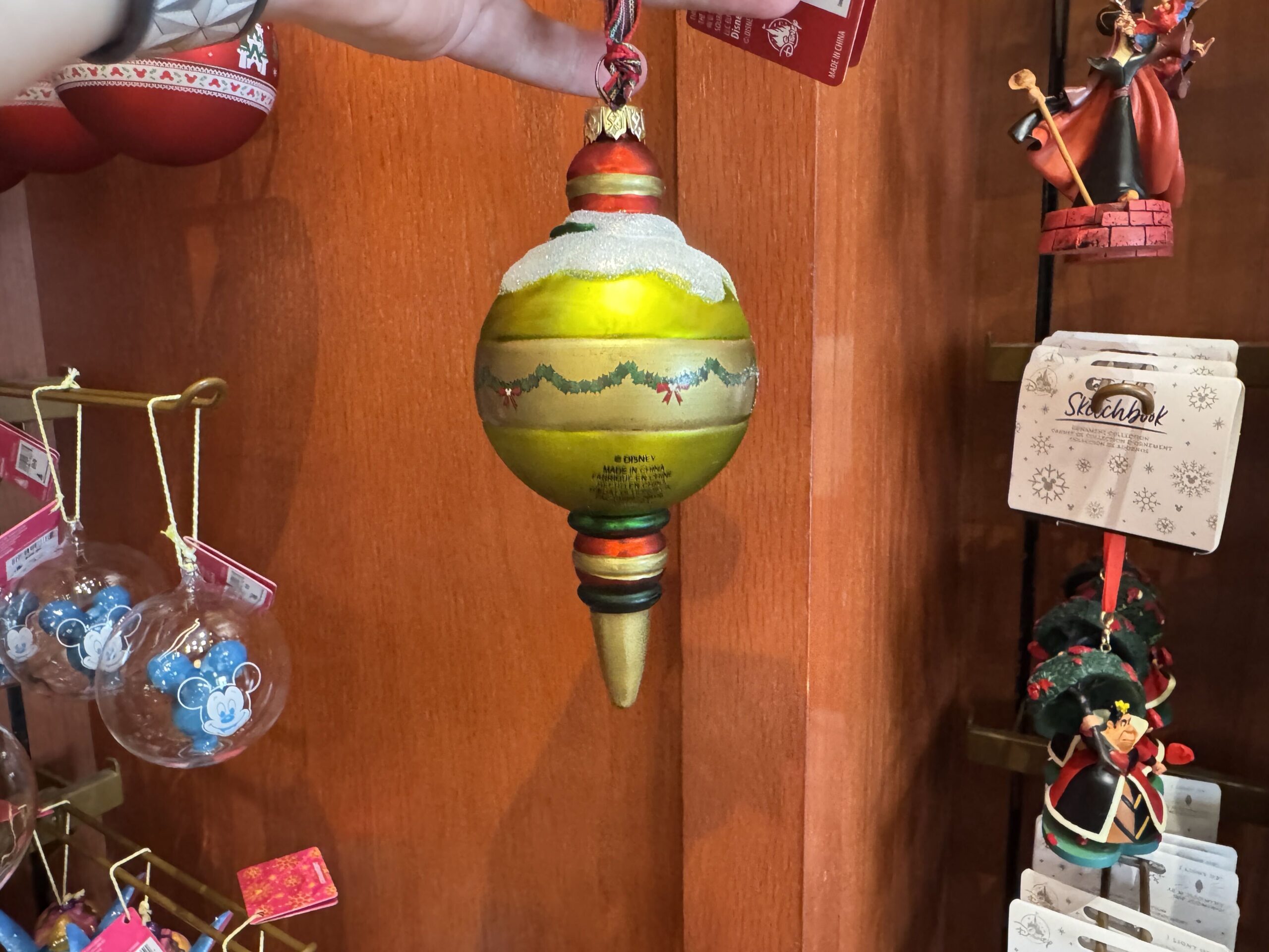 The back of the ornament is light green and painted to be strung with Christmas garland and bows, as we see Mickey decorate his home for the holiday in the film.