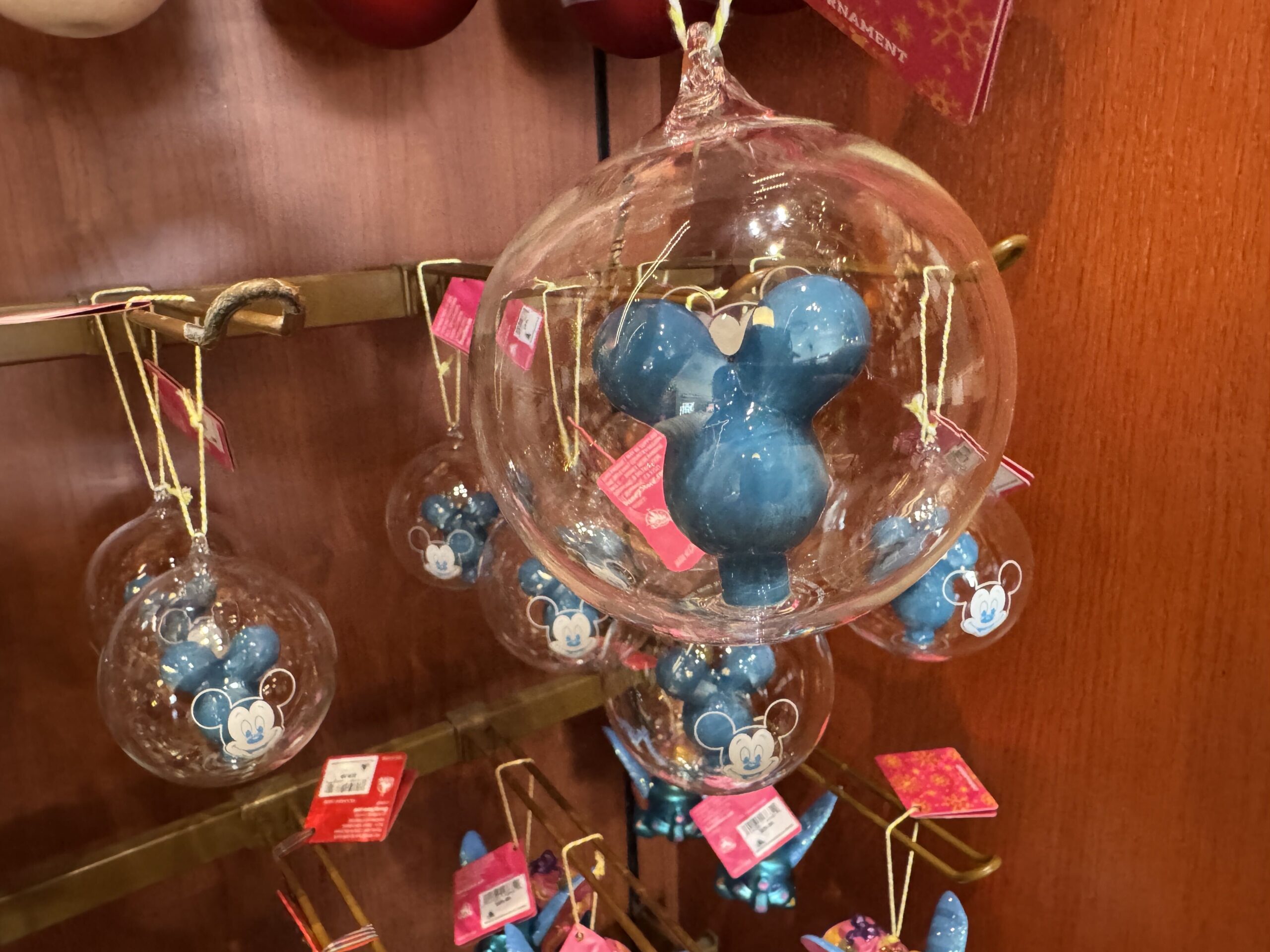 This clear glass ornament features a classic blue Mickey balloon inside. The front of the glass is painted with Mickey's face in white, mimicking a Main Street Mickey Balloon in miniature form.