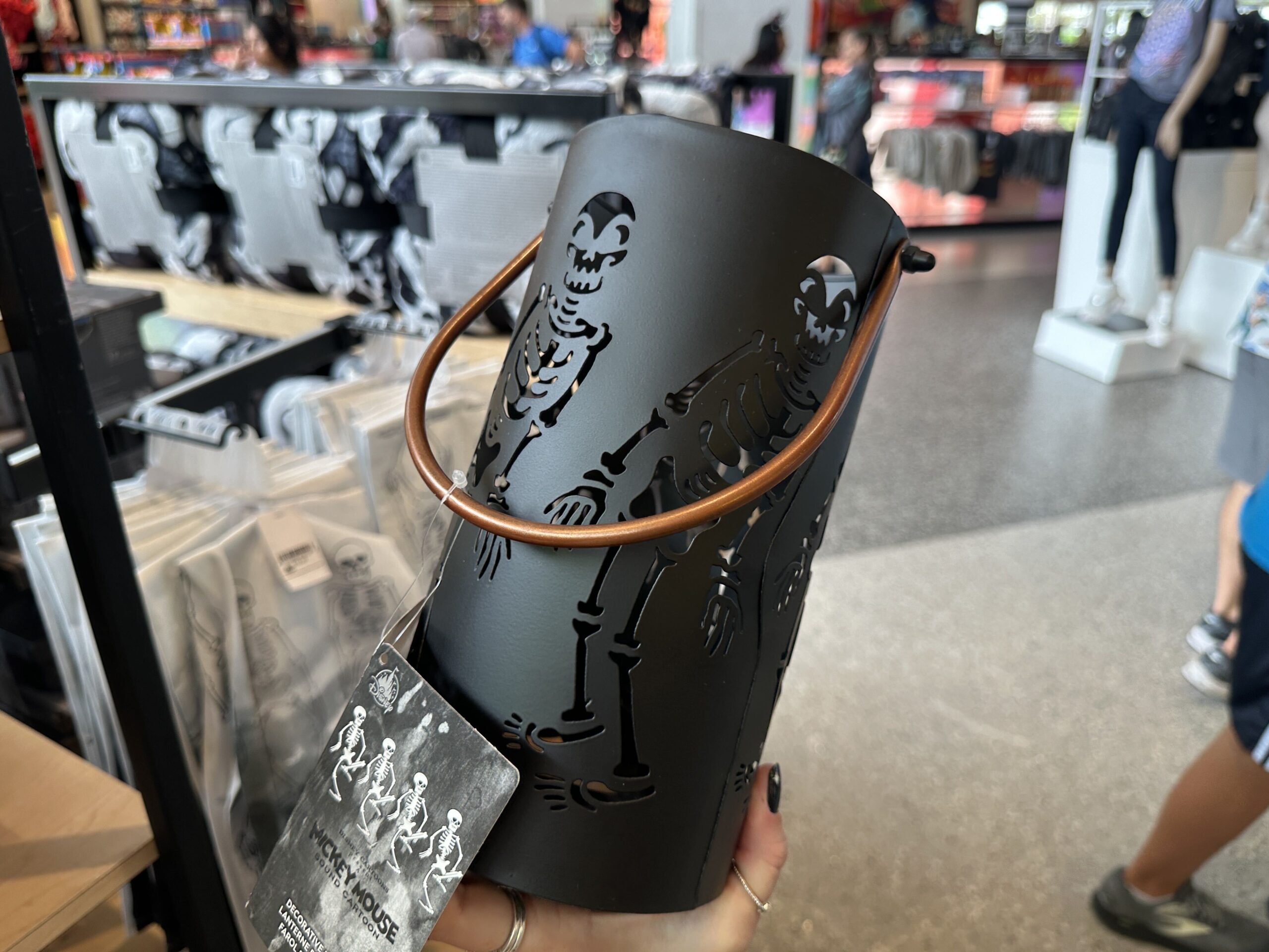 The skeletons are cut out of this black, metal lantern. It has a brown handle and a place to hold a candle on the inside. When lit, the skeleton cut-outs glow with the light.
