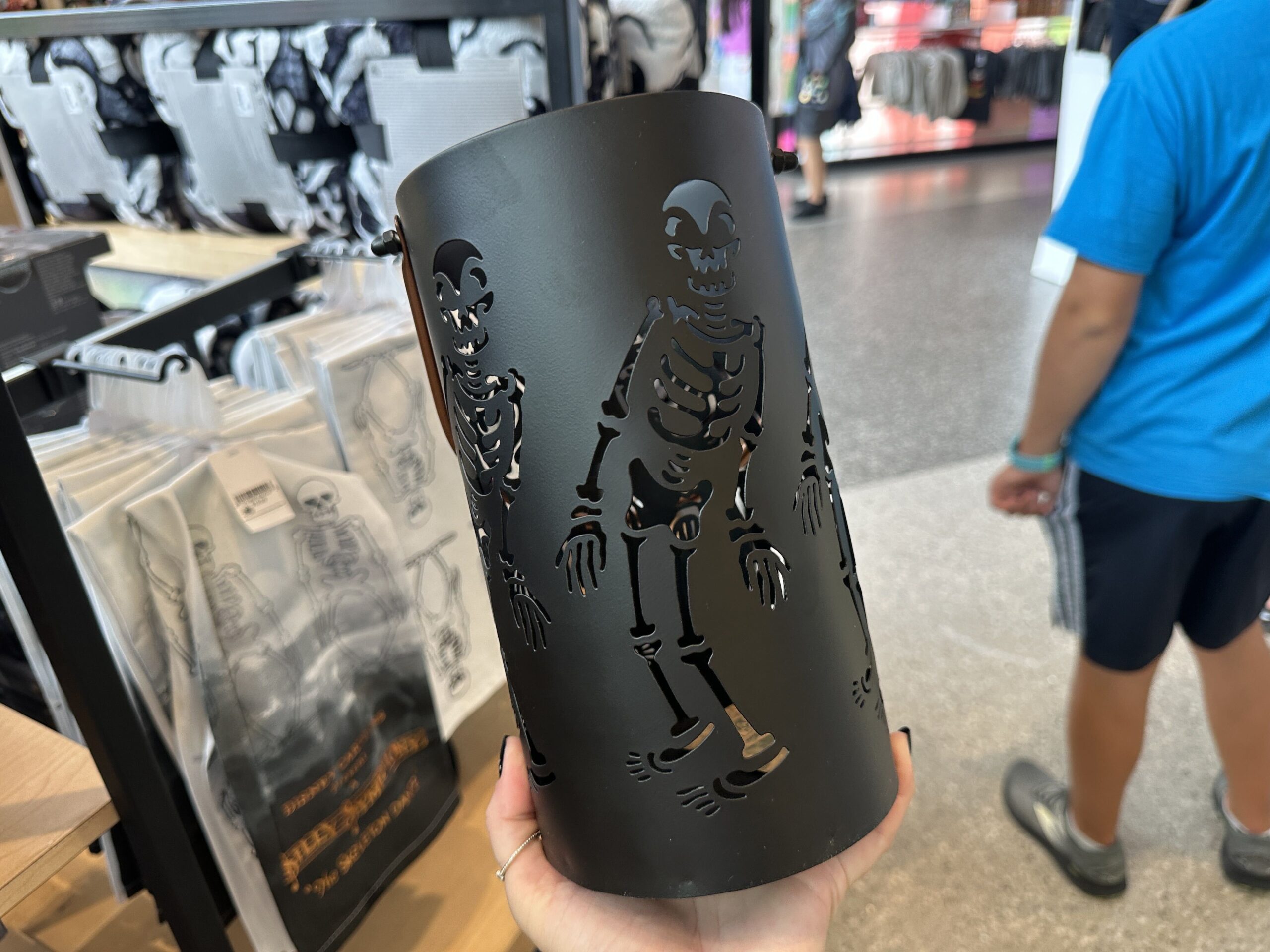 The skeletons are cut out of this black, metal lantern. It has a brown handle and a place to hold a candle on the inside. When lit, the skeleton cut-outs glow with the light.