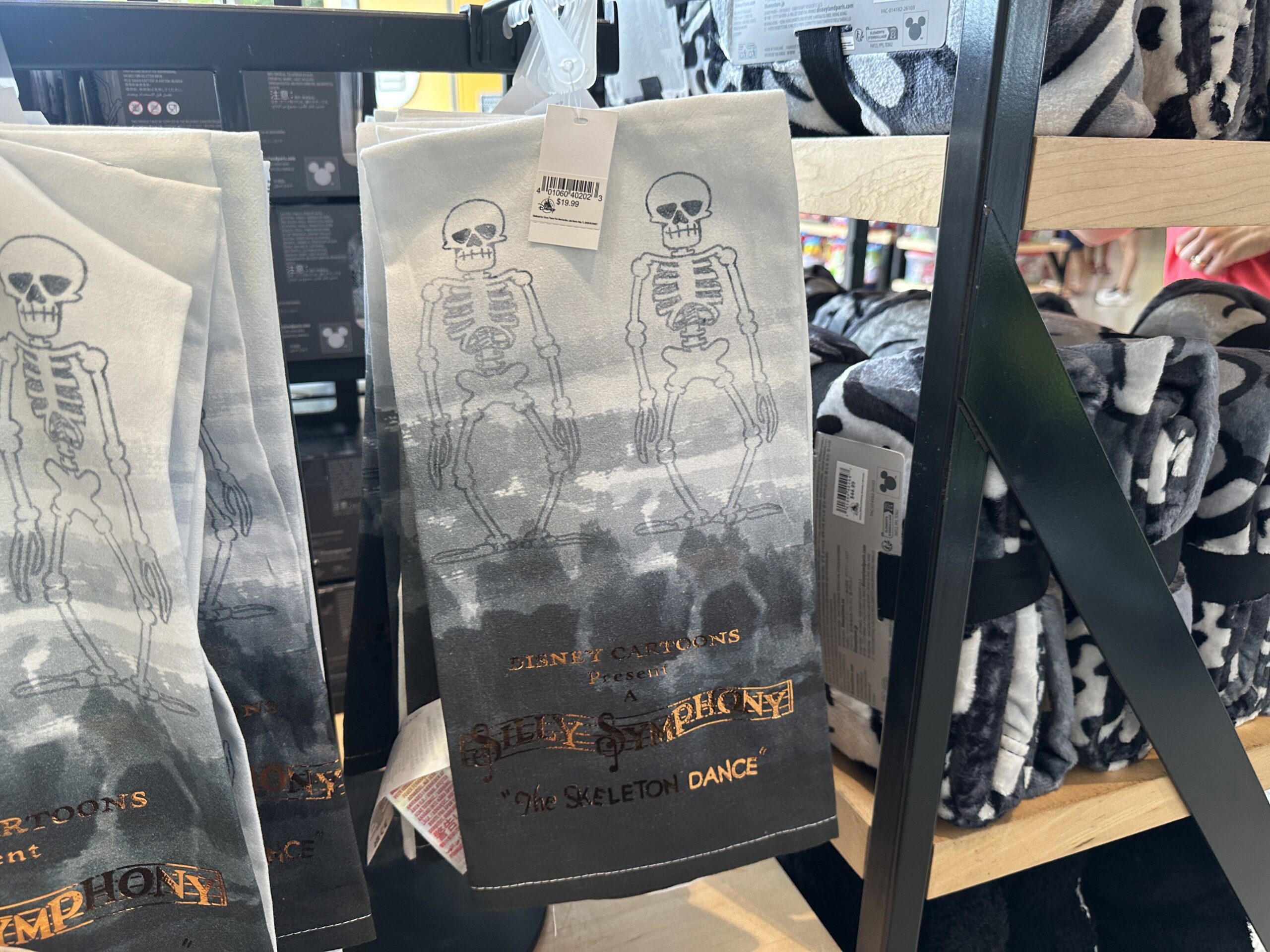 This towel is an ombre gray color with two skeletons at the top. "Disney Cartoons Presents a Silly Symphony 'The Skeleton Dance'" is written in gold text at the bottom.