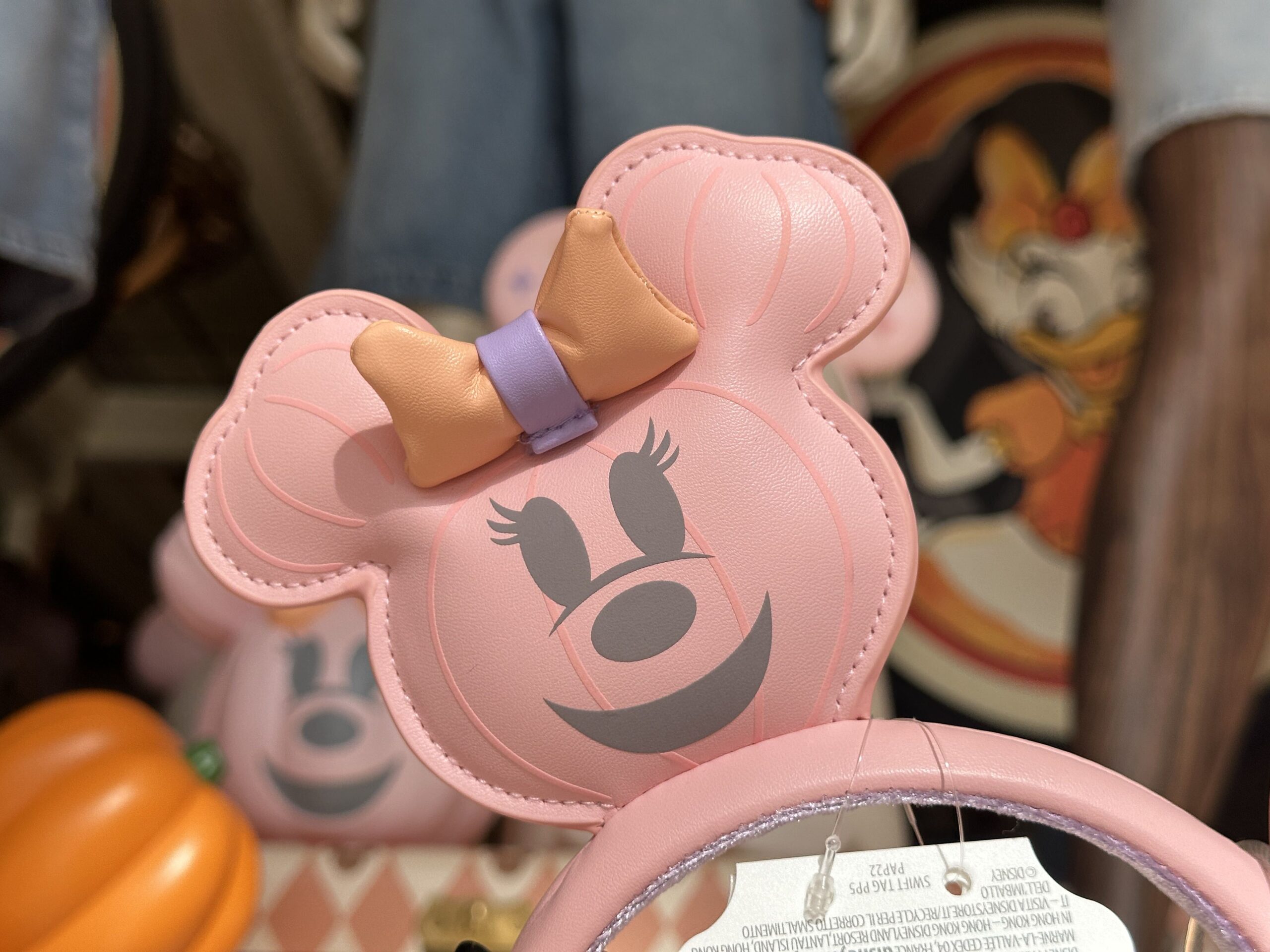 The pink ear headband includes a Minnie jack-o'-lantern wearing a three-dimensional orange and purple bow on each ear.