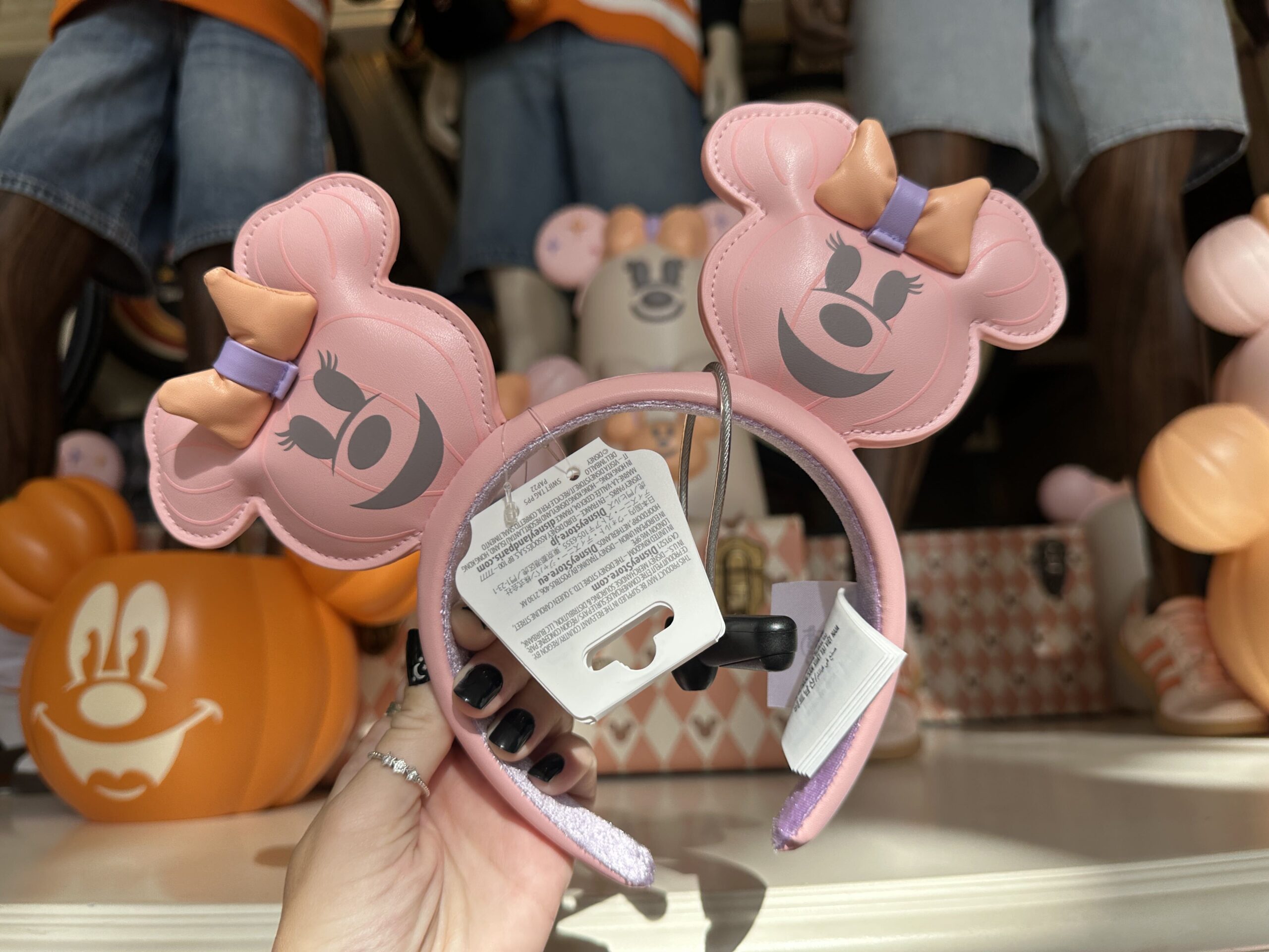 The pink ear headband includes a Minnie jack-o'-lantern wearing a three-dimensional orange and purple bow on each ear.