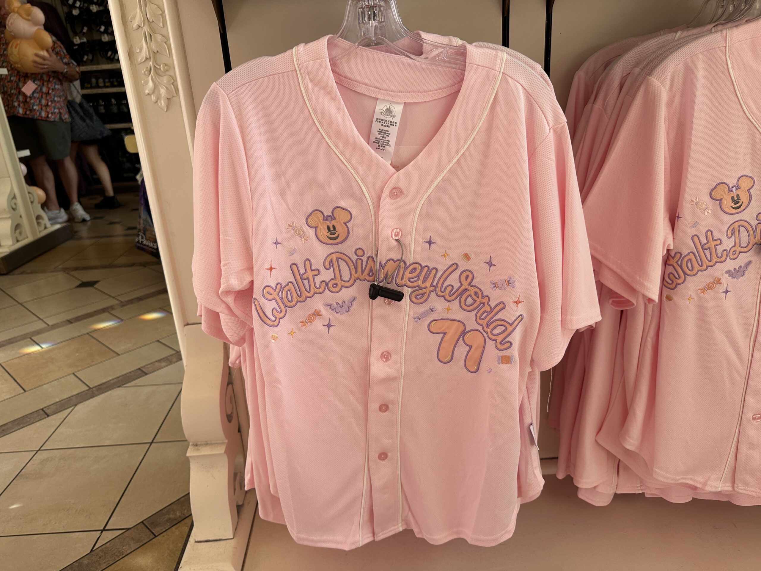 The sports jersey buttons down the front and features "hey boo" text surrounded by a Mickey pumpkin, bat, and sparkles. The back has a large image of a Mickey ghost holding a candy bucket. He is surrounded by jack-o'-lanterns, bats, and sparkles.