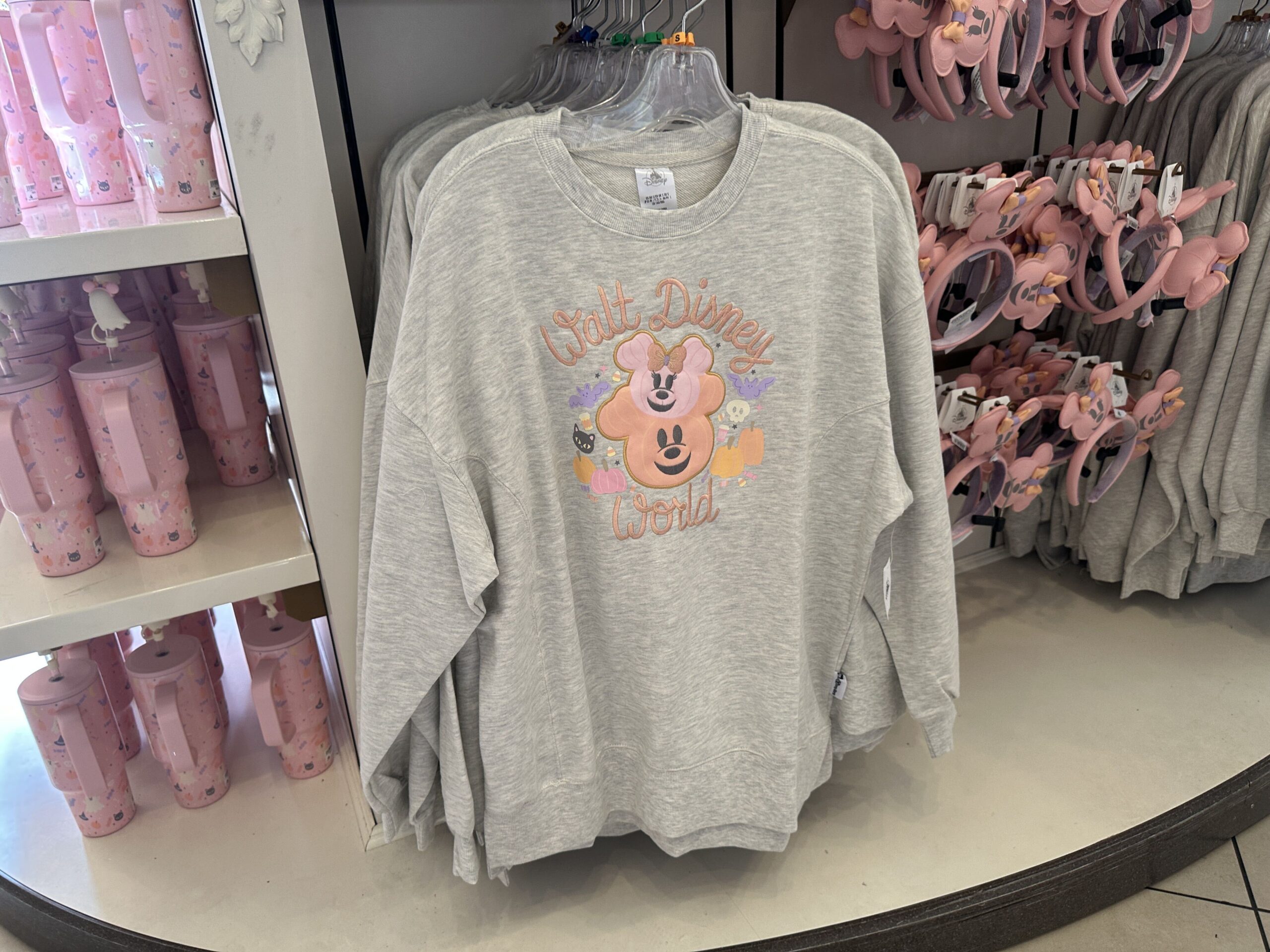The heathered gray colored pullover sweatshirt features "Walt Disney World" script in light orange, as well as Mickey and Minnie jack-o'-lantern appliques and other Halloween-themed art.