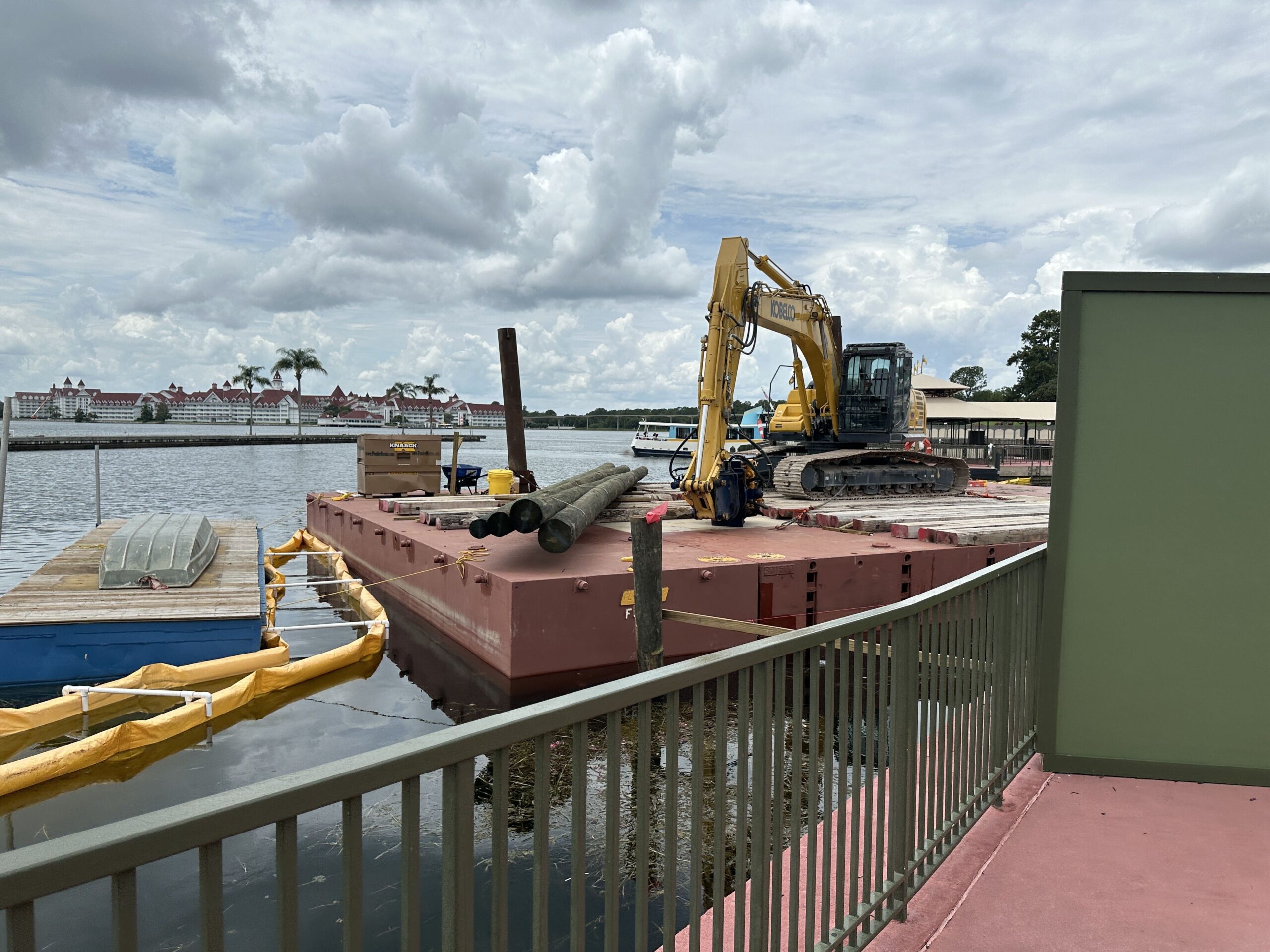 Long pieces of wood are now staged for the Magic Kingdom ferryboat dock expansion. A week ago, a floating platform arrived on site for equipment and a construction vehicle.