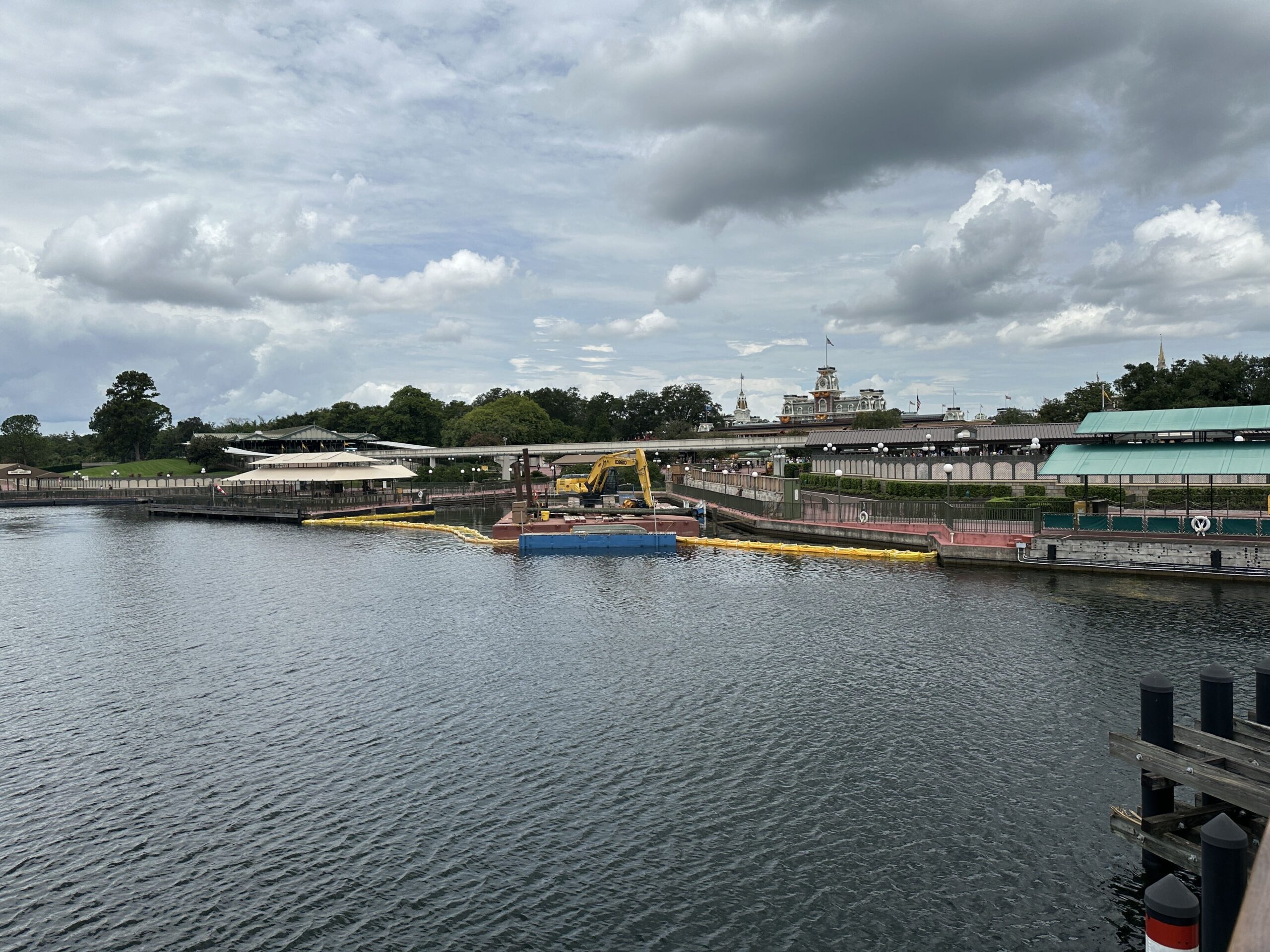 Long pieces of wood are now staged for the Magic Kingdom ferryboat dock expansion. A week ago, a floating platform arrived on site for equipment and a construction vehicle.