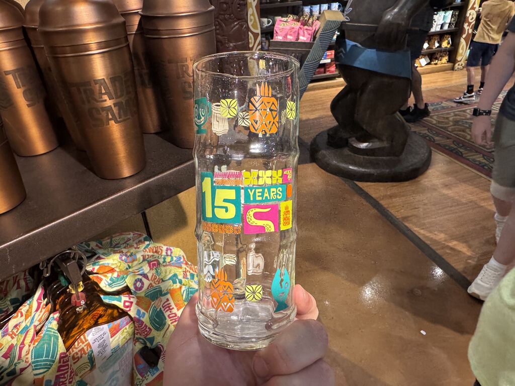 On the back, "15 Years" is printed in yellow lettering with a teal border. A variety of different tiki-inspired designs are printed on the glass.