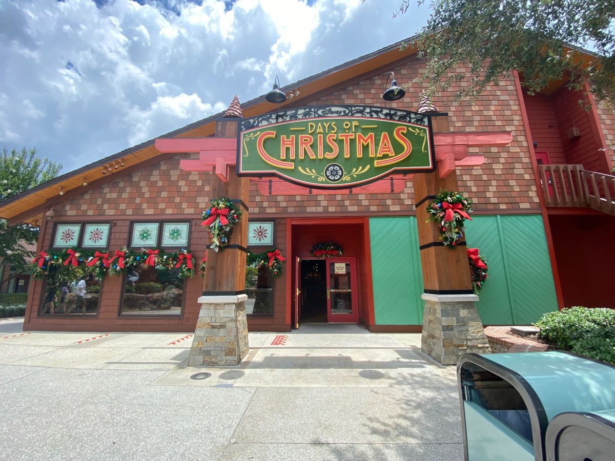Days of Christmas shop in Disney Springs. The shop has a wood log cabin exterior with steep roofs and Christmas garlands.